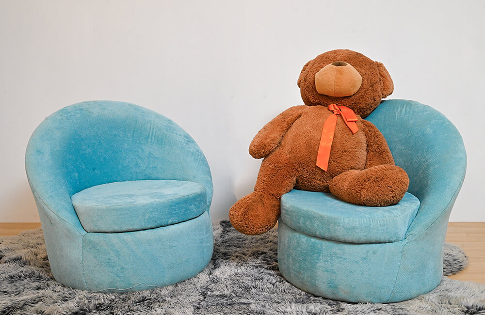 a toy teddy bear sitting on a blue chair.
