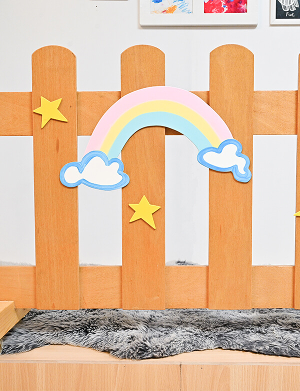 a wooden fence with a rainbow and clouds
